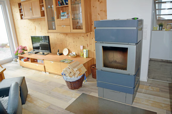 Mit Pellets und Scheitholz lässt sich der Ofen heizen. Dahinter eine Massivholzwand aus Brettsperrholz verkleidet mit Zirbe be